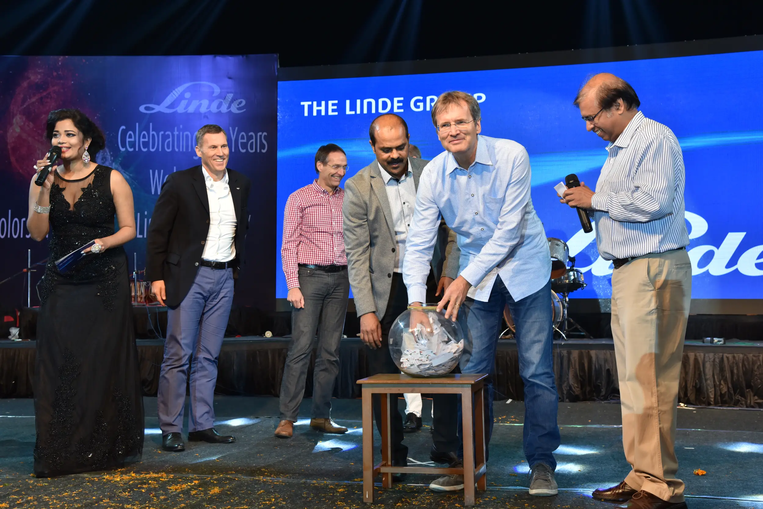 Man and woman speaking on stage at night with blue lighting